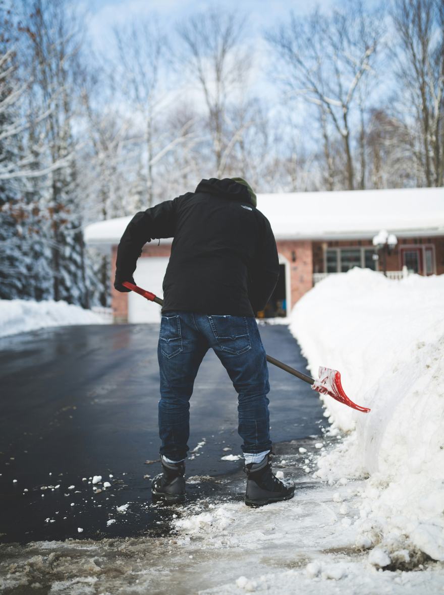 Shoveling a driveway beside a waist-high snowbank.